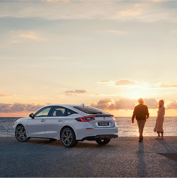 Honda Civic Hybrid parked next to a sea, people standing on the right side of the car.